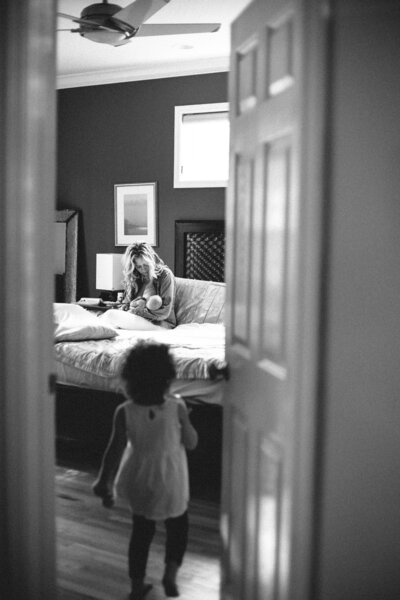 Photographer Alison Amick captures an intimate moment between mom, baby and big sister in black and white