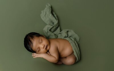 Mother-and-baby newborn session in Plano, Texas. The intimate scene shows a mother that cradles her precious newborn, capturing the essence of love and connection