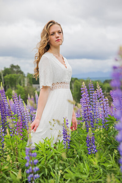 Senior girl in field of lupin flowers | Taken by Maine Photographer