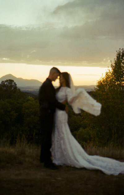 A 35mm film image of a couple on their wedding day facing each other having a romantic moment at sunset.