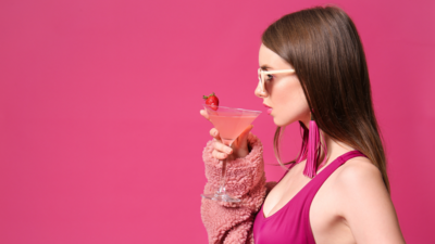 a stylish woman wearing pink while sipping pink margarita