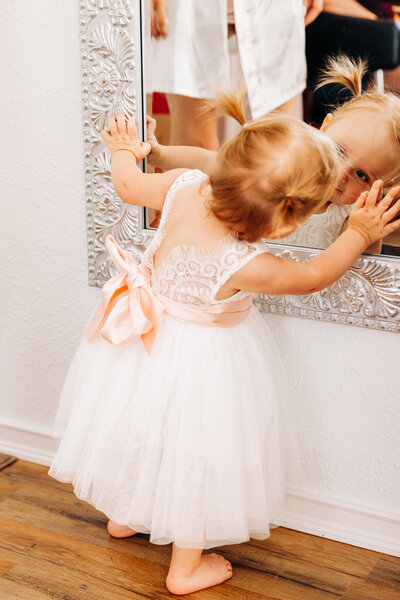 Baby flower girl looking at herself in mirror at Flathead Lake Forevers, Montana