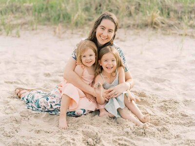 mother snuggling daughters By Carrie Pellerin