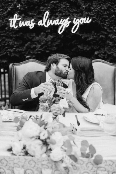 A couple kisses while toasting.