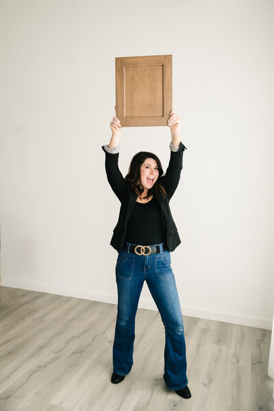 A women holds a wooden cabinet door above her head