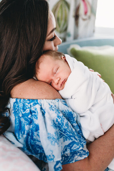 mother holding newborn daughter at home in nursery