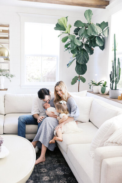 Image of young family cuddling on the couch looking at new baby, taken by Sacramento Newborn Photographer Kelsey Krall Photography