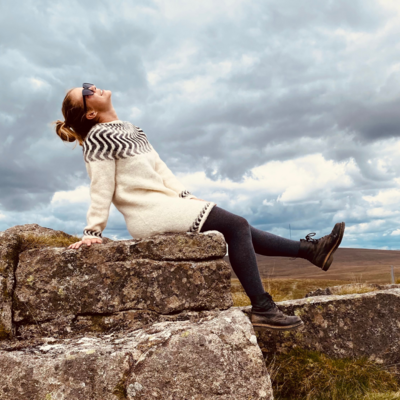Lady sits on top of a rock looking at the sky