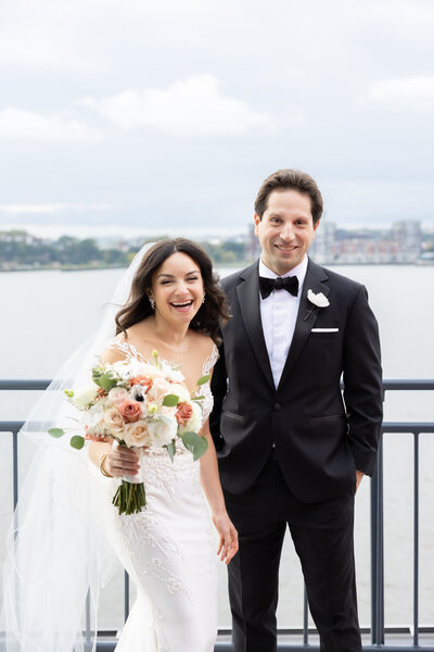A bride and groom laugh at the camera on the balcony of Sunset Terrace