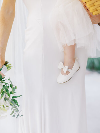 closeup detail of flower girl's shoe as bride holds flower girl before wedding