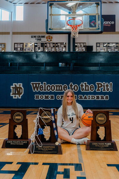Girl basketball player poses for the camera in high school gym.