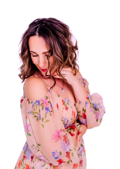 woman posing in a whimsical floral dress with wavy hair looking demure