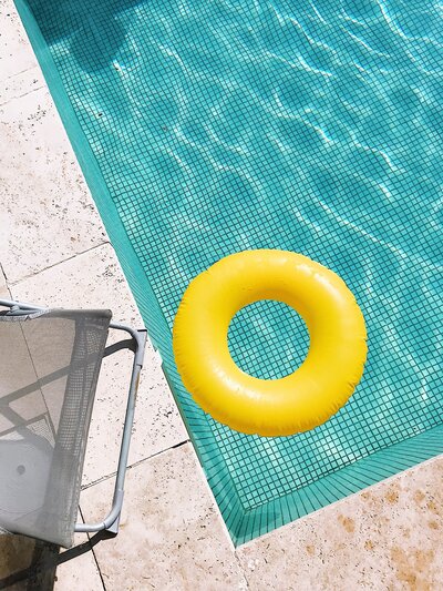 A bright yellow inflatable pool tube floating at the end of a pool shot from above for restaurants and bars photography socialfizz