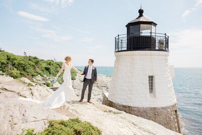 Couple looking at each other holding hands in front of a lighthouse in Newport Rhode Island