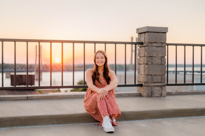 Teenage girl poses for the camera on a balcony at sunset.