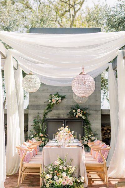 Elegant wedding reception designed by a San Luis Obispo wedding planner, featuring romantic floral arrangements, soft draping, and crystal chandeliers.