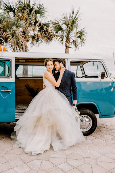 Bride and groom holding each other in from of a vw bus  at the lsland hotel in Fort Walton Beach, FL
