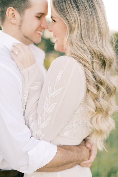 blonde woman wearing cream top embracing fiancé  during
