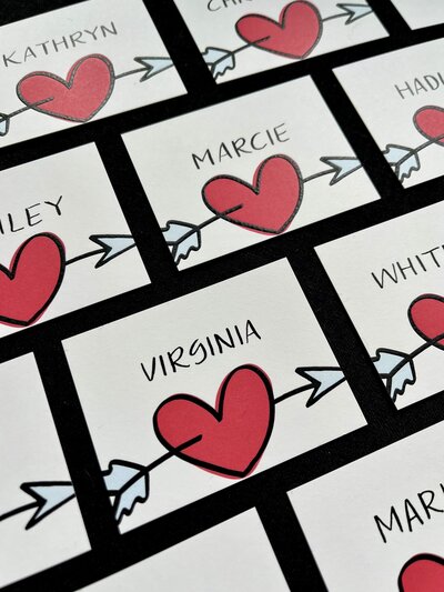 Place cards with red heart illustration and black calligraphy