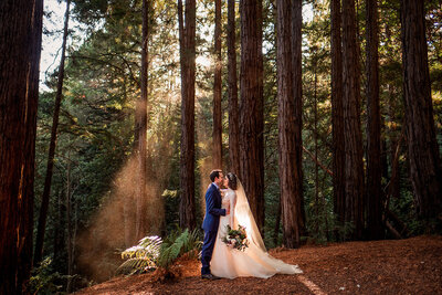 Bride and groom are standing in the forest exchanging wedding vows at Sequoia Retreat Center in Santa Cruz.