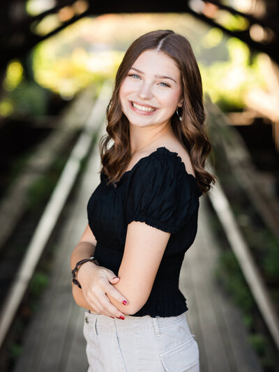 high school senior girl in black shirt posing on shooters bridge in cleveland for senior photos 