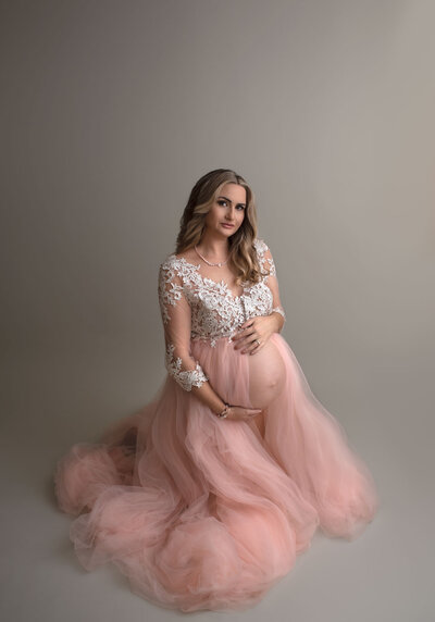 pregnant woman kneeling in pink and lace gown  by st. louis photographer, sutherland photography