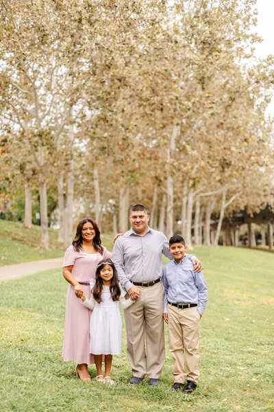 Family portrait under the Sabine Bridge in Houston with a family of four smiling and holding hands