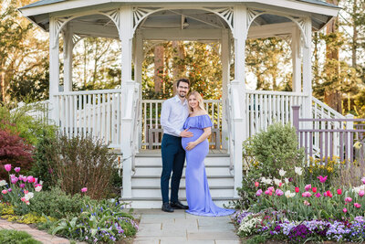 An expecting couple looking into each other's eyes among the tulips at Green Spring Gardens.