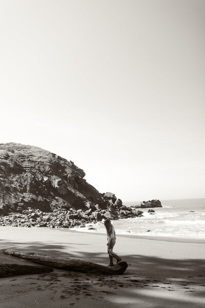Abby Ree Photography walks on a log near the coastline in Southern Oregon.