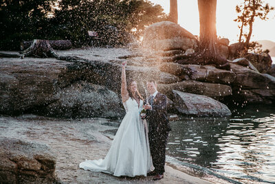 Bride and groom popping champagne and celebrating on the shoreline in San Francisco beaches.