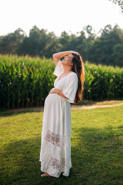 pregnant mother naturally posed with cornfields and summer green in background
