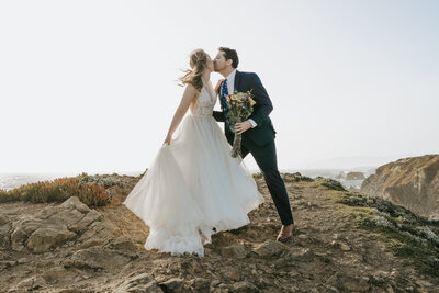 bride and groom kissing on mountain