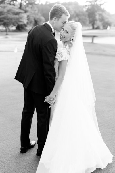  A radiant bride in an elegant gown smiles amid lush greenery and blooming flowers, glowing with happiness