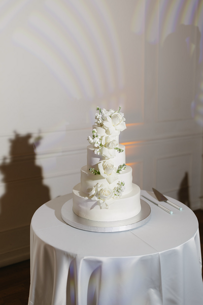 Modern white four-tier wedding cake captured through documentary style wedding photography in Cabo | Sush Digital Media