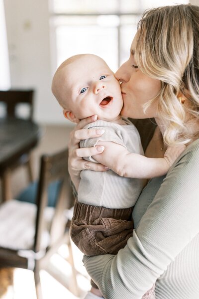 mom kissing baby and baby smiling in-home peoria illinois photos 