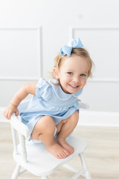 Girl dressed in blue sitting on chair