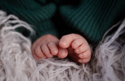newborn baby toes with dark emerald outfit and fuzzy blanket