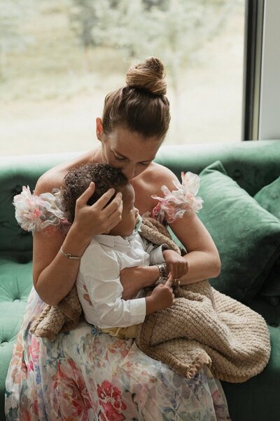 Mother snuggling baby on couch by a Michigan photographer