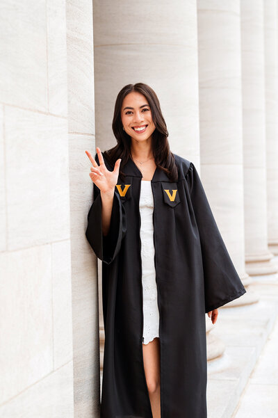 Vanderbilt grad in white dress and graduation robe throwing anchor down on steps of Wyatt Center
