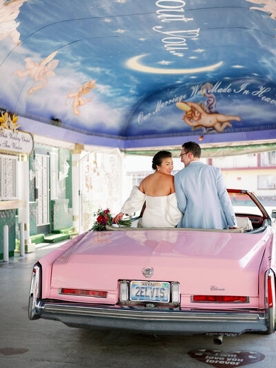 newlyweds sit in pink convertible