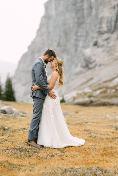 This stunning image captures the bride and groom holding each other, surrounded by the majestic mountains of the national park. The vast landscape emphasizes the closeness and love shared between them on their special day.