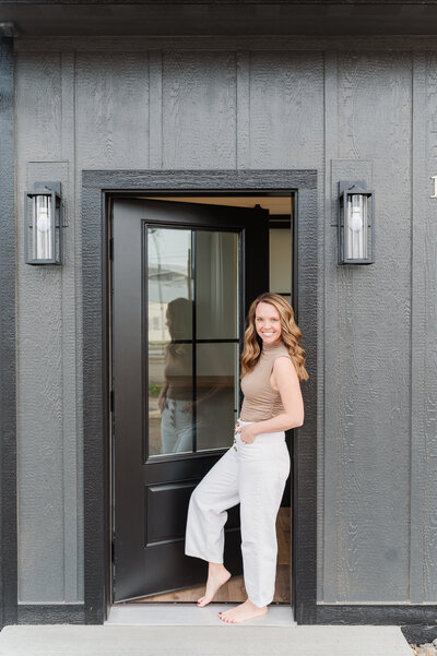 Jessica Bean, an LC Valley real estate investor posing in a doorway of an investment property for her branding session. 