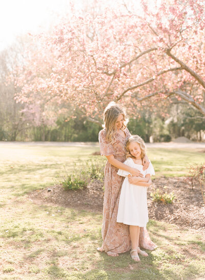 Mom and daughter hold hands in a field during their Wake Forest family photography session. Photographed by Family Photography Raleigh A.J. Dunlap Photography.
