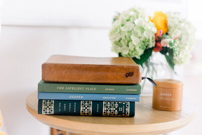 Stack of religious books and a Bible on a table with flowers