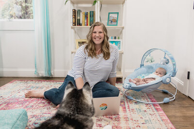 Woman sitting on office floor with dog and baby