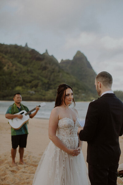 Bride and groom read vows as officiant plays the piano behind them
