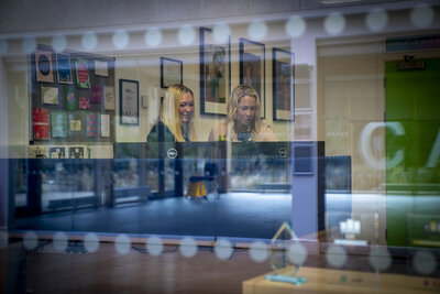 two ladies looking at a computer through their office window