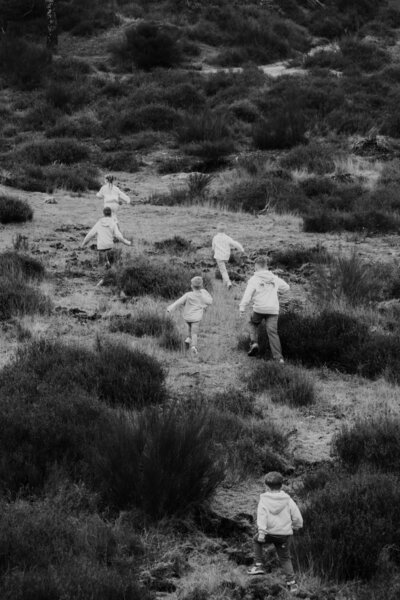 Zwart-witfoto van kinderen die door het gras rennen, met een dynamische en energieke uitstraling.