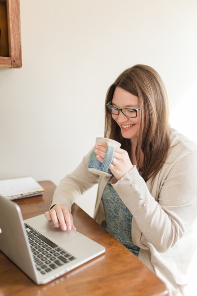 Photographer working on laptop with coffee and smiling