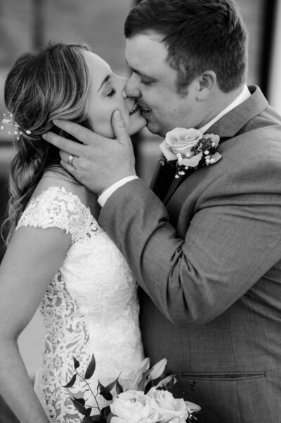 little rock ar wedding photogrpaher captures bride and groom kissing passionately as the groom holds the brides jawline during their outdoor wedding photos